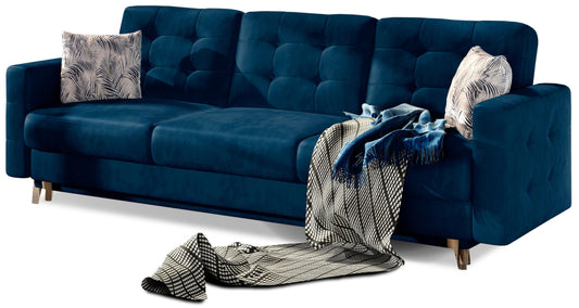 Kanapa Asgard w kolorze Monolith 77 niebieski z poduszkami w tkaninie Botanical 80 wielokolorowej – elegancka sofa trzyosobowa z pikowanym oparciem i drewnianymi nogami.