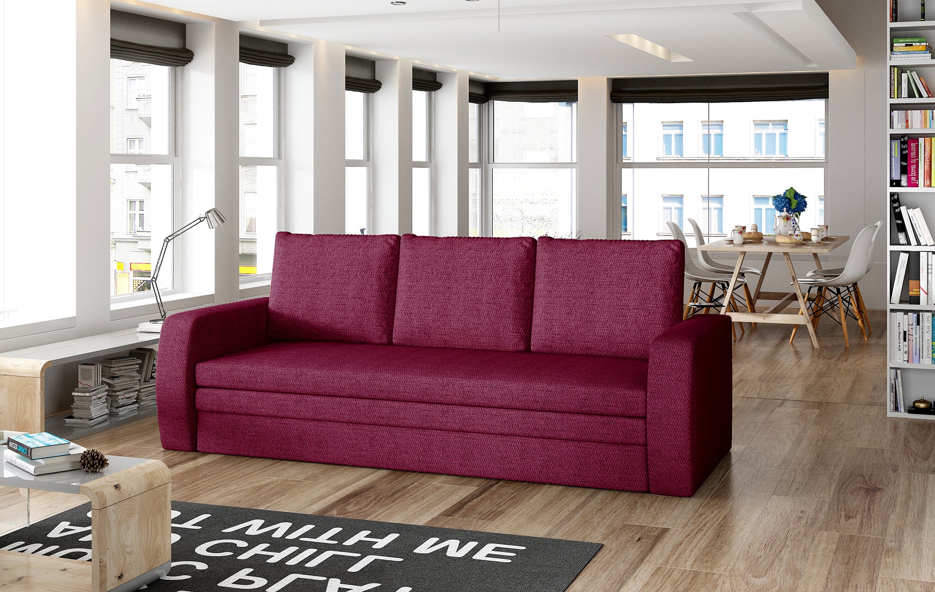 Sofa Inversa w odcieniu Malmo 63 czerwony ustawiona w nowoczesnym, jasnym salonie z jadalnią w tle.