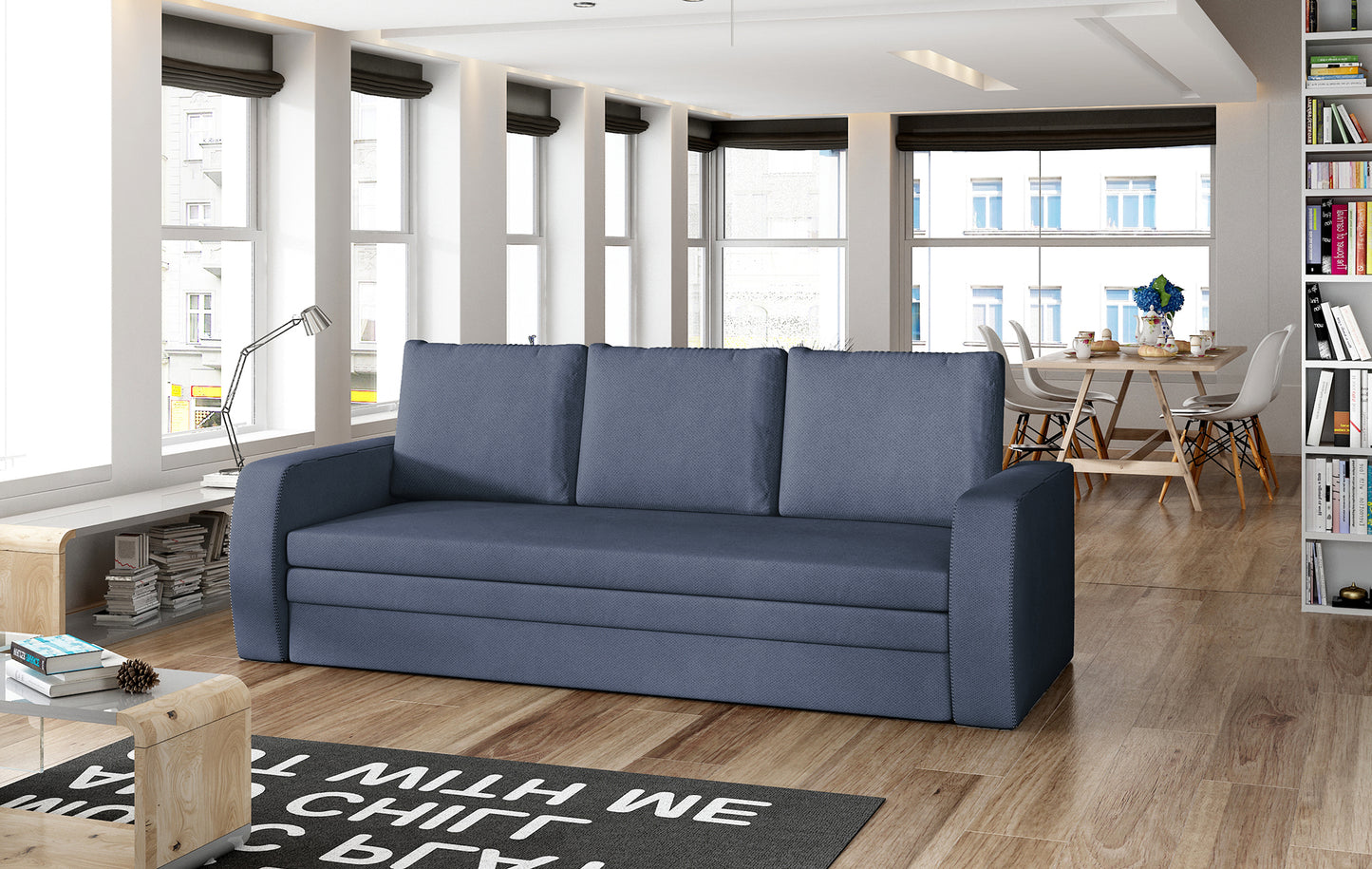 Sofa Inversa w odcieniu Soro 76 granatowy ustawiona w nowoczesnym, jasnym salonie z jadalnią w tle.