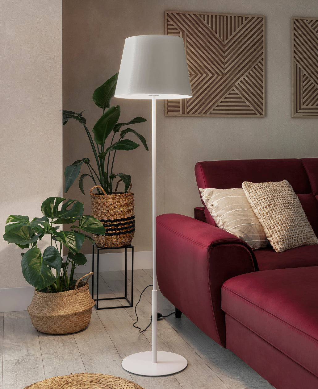 Lampa Vespillo 1a włączona przy zmierzchu, emitująca ciepłe światło z abażura i tworząca przytulny nastrój w nowoczesnym salonie.