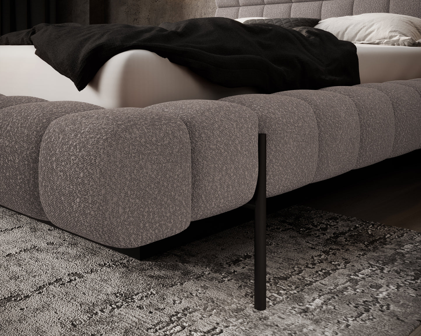 Detal narożnika łóżka Magentta w tkaninie Jaffray 03 szary, z miękkim, pikowanym wykończeniem i metalową, czarną nogą.