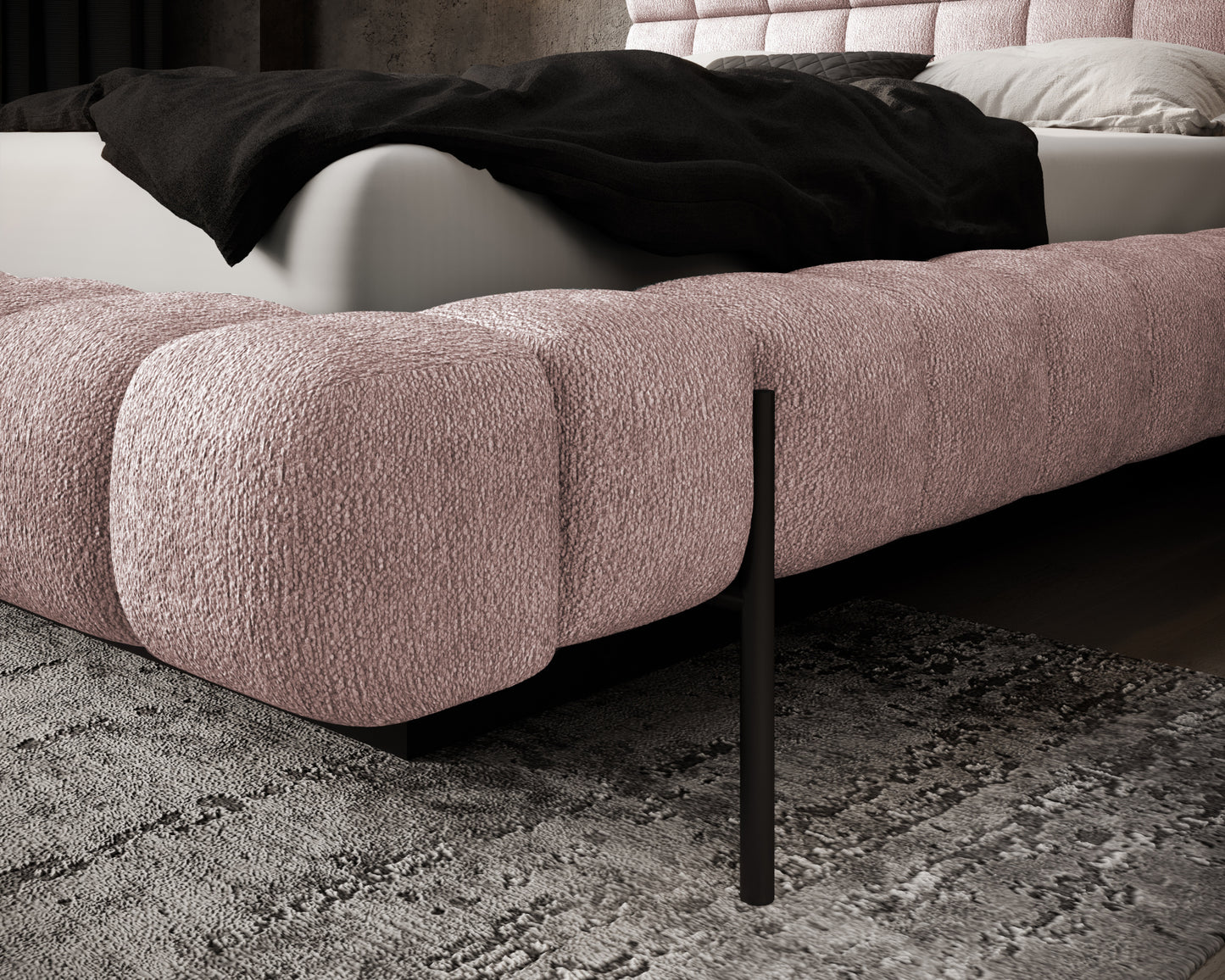 Zbliżenie na narożnik łóżka Magentta w tkaninie Touch 24 różowy z widoczną fakturą, czarną nóżką i fragmentem dywanu.