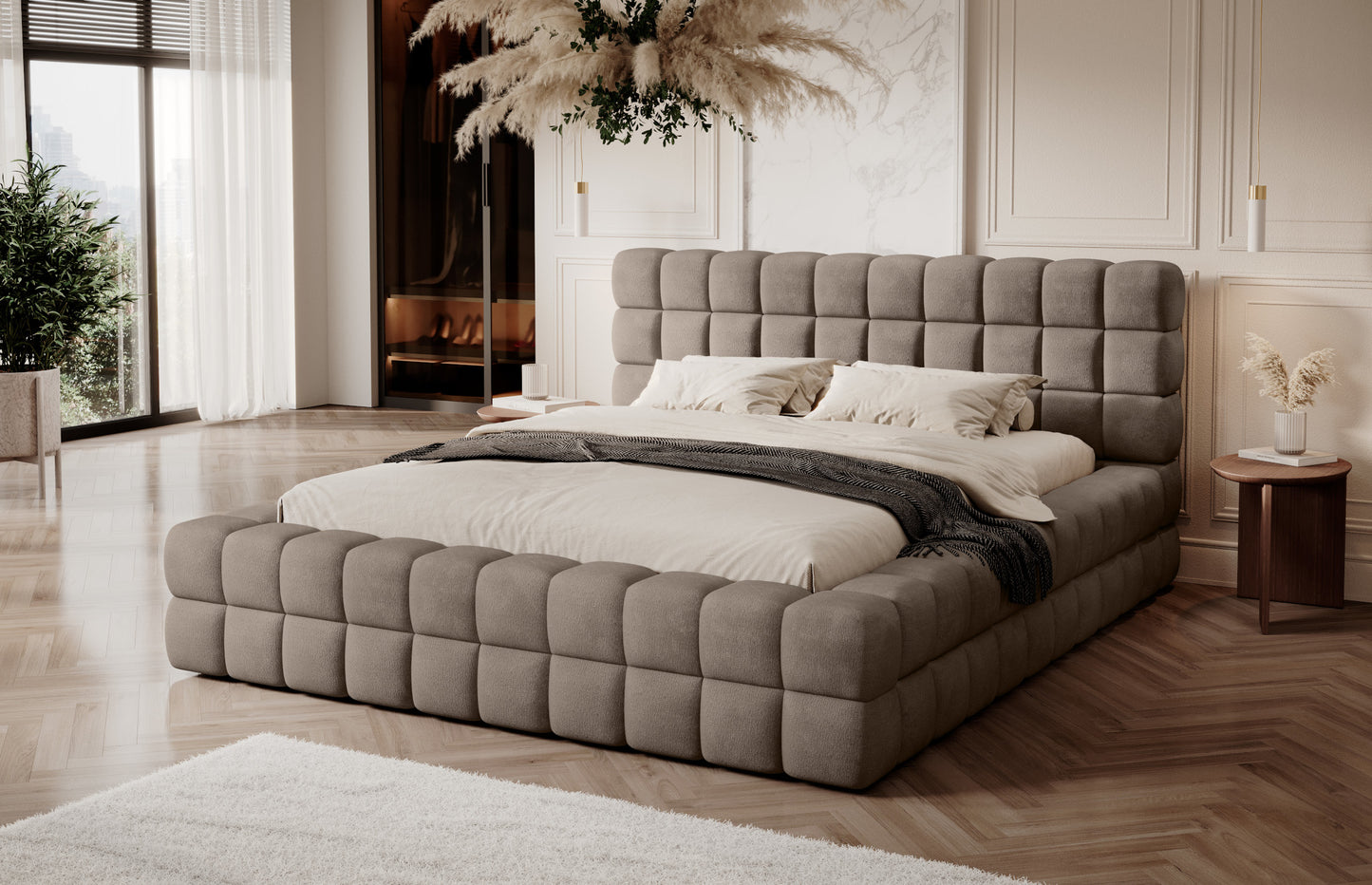 Łóżko tapicerowane Dizzle 180x200 cm w tkaninie Amore 20 jasnobrązowy, ustawione w eleganckiej sypialni z dużymi oknami, jasnymi zasłonami i drewnianą podłogą, ujęcie z przodu w naturalnym świetle.