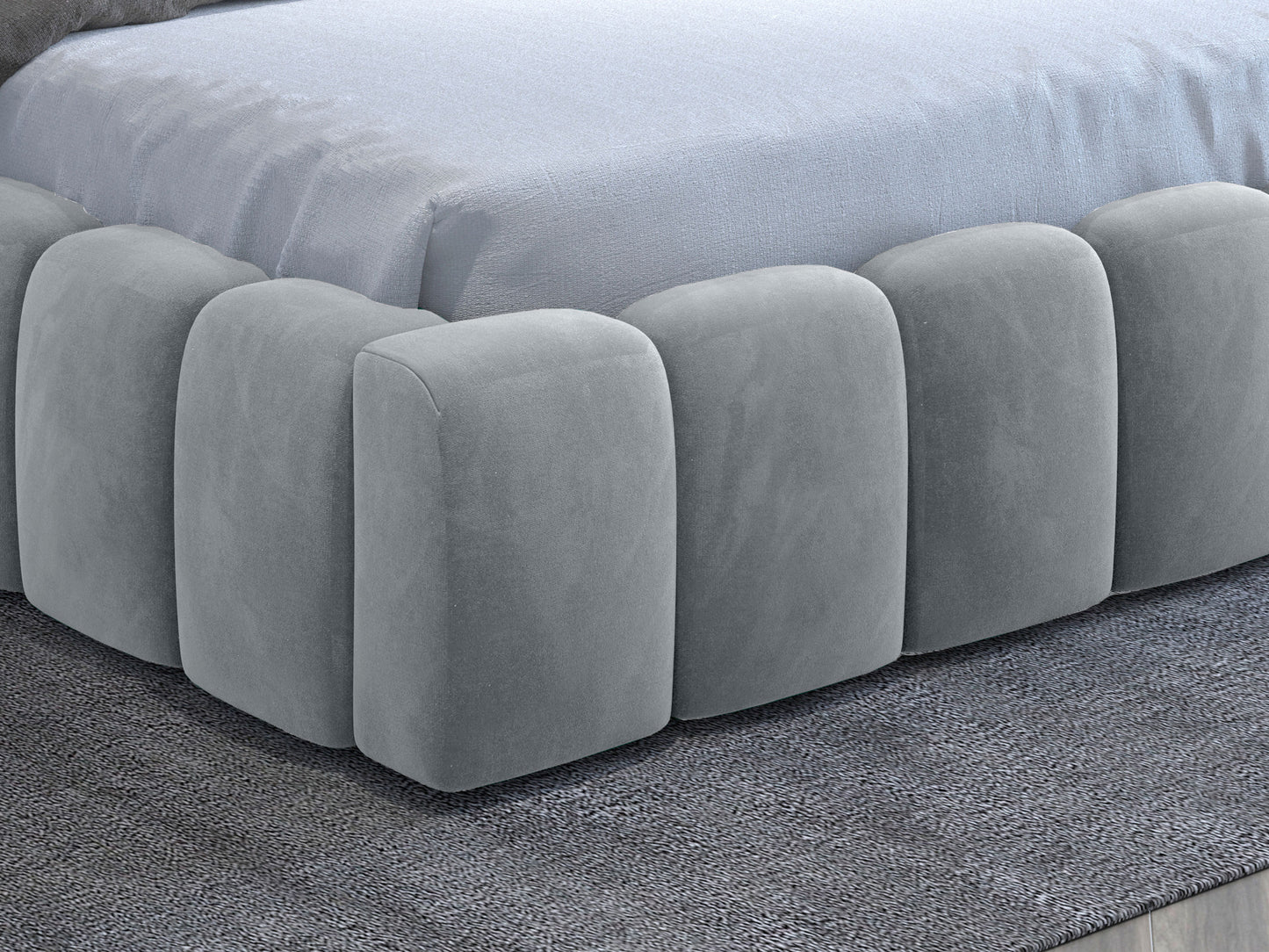 Boczny detal tapicerowanej ramy łóżka Lamica II 160x200 cm w kolorze jasnoszarym Monolith 84 na tle dywanu.