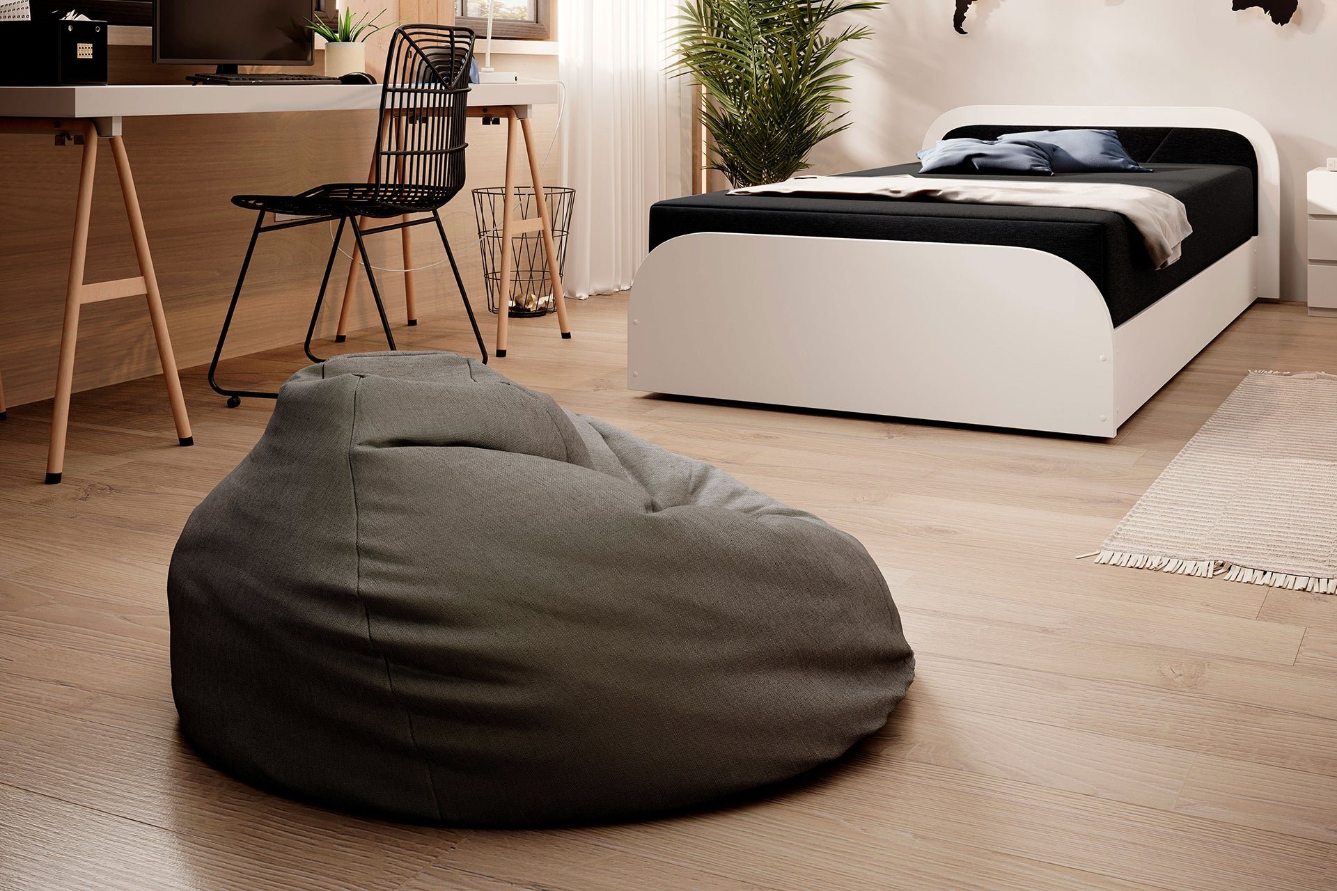 Perspektywa pokoju z łóżkiem Parys II w tapicerce Sawana 21 czarny w lewym układzie, miękka pufa-worek na jasnej, drewnianej podłodze, w tle biurko z metalowym krzesłem.