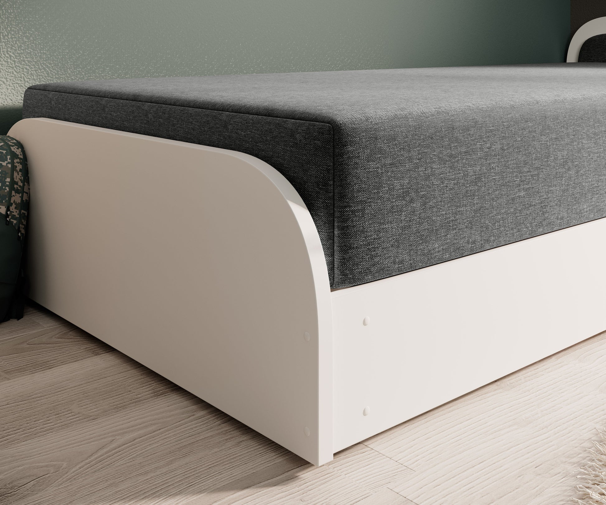 Zbliżenie na dolną krawędź prawego boku łóżka Parys I: biała, zaokrąglona płyta i struktura ciemnoszarej tkaniny Sawana 21.