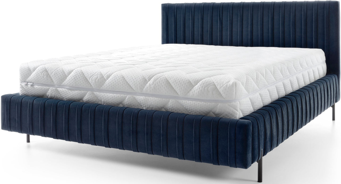 Frontowy widok łóżka Plissa 140×200 Velvetmat 40 granatowego z białym pikowanym materacem i cienkimi czarnymi nogami na białym tle.
