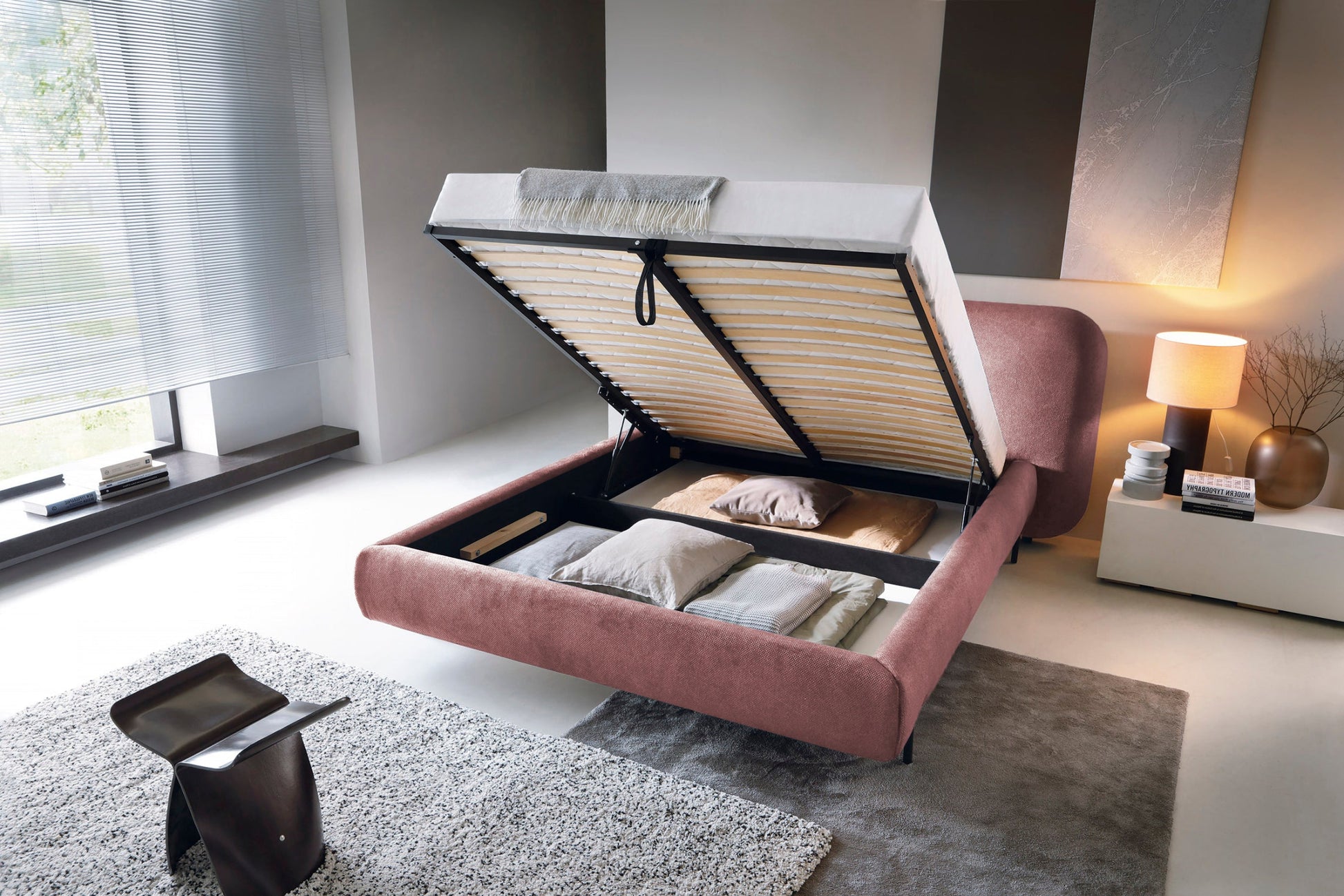 Łóżko Pointt Paolli 24 różowe – widok z boku z uniesionym stelażem, prezentujący pojemnik na pościel z wypełnieniem i poduszkami w aranżacji wnętrza.