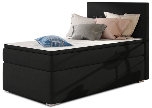 Łóżko kontynentalne Rocco w kolorze Sawana 14 czarny, układ lewy – widok studyjny z przodu, prezentujące eleganckie, tapicerowane wykończenie w głębokiej czerni oraz prosty, nowoczesny zagłówek.