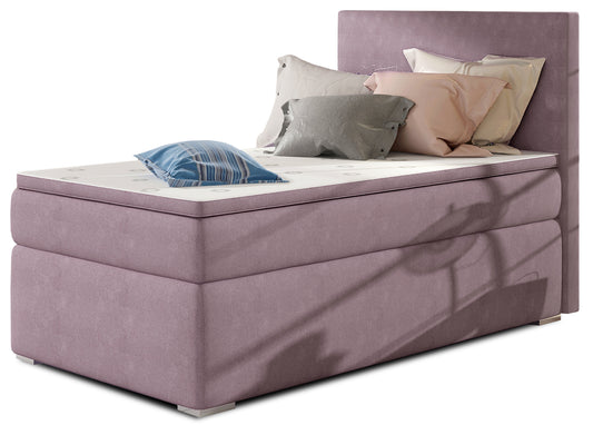 Łóżko kontynentalne Rocco w kolorze Soro 65 jasnofioletowy, układ lewy – widok studyjny z przodu, prezentujące tapicerowane wykończenie w pastelowym odcieniu fioletu oraz elegancki, prosty zagłówek.