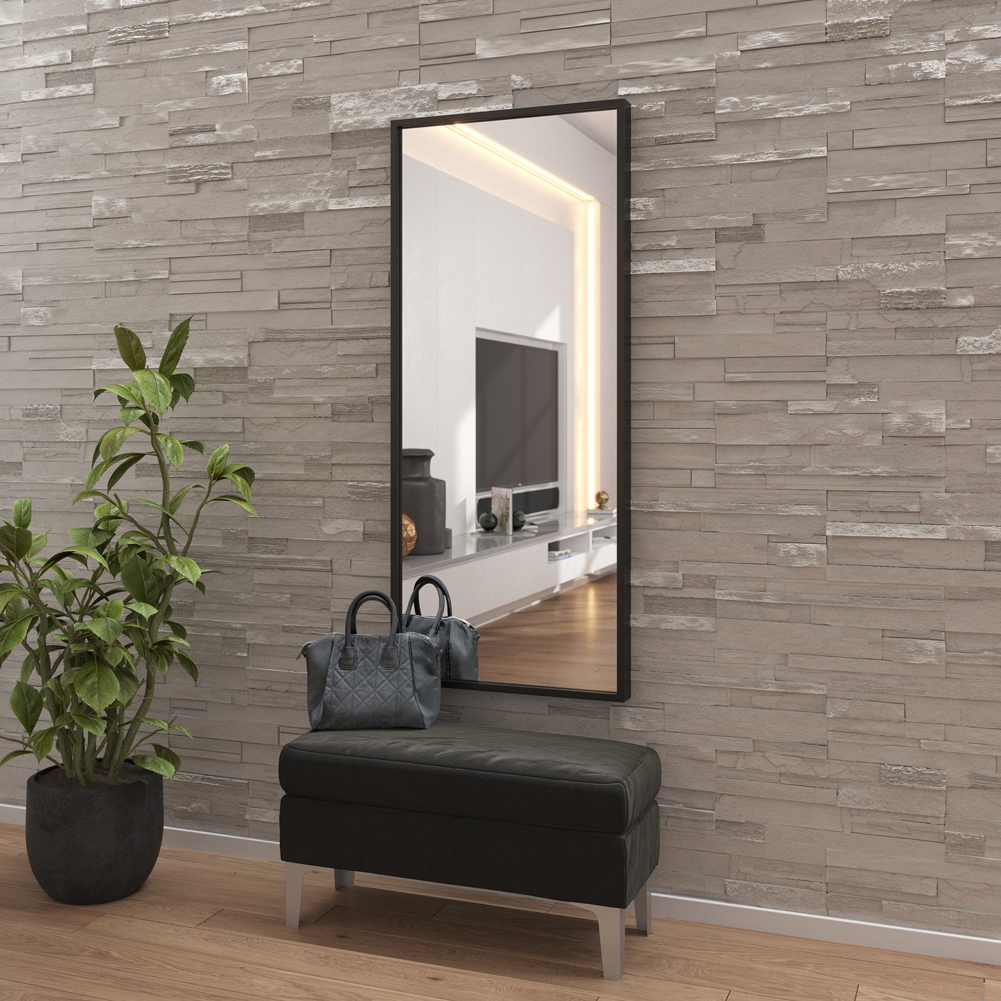 Czarne lustro Vasto zawieszone na ścianie wyłożonej kamiennymi płytkami, z odblaskiem salonu, nad czarną ławeczką i obok rośliny doniczkowej.