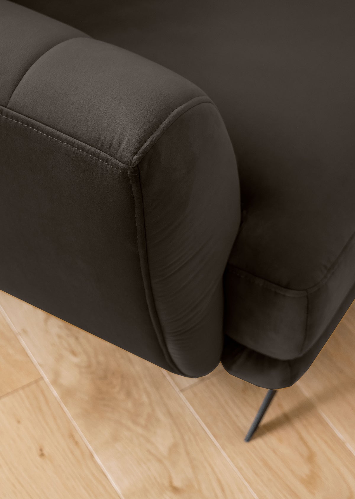 Sofa z fotelem i pufą Megis w tapicerce velvet o głębokim czarnym kolorze. Spójny design tworzy harmonijną przestrzeń wypoczynkową.