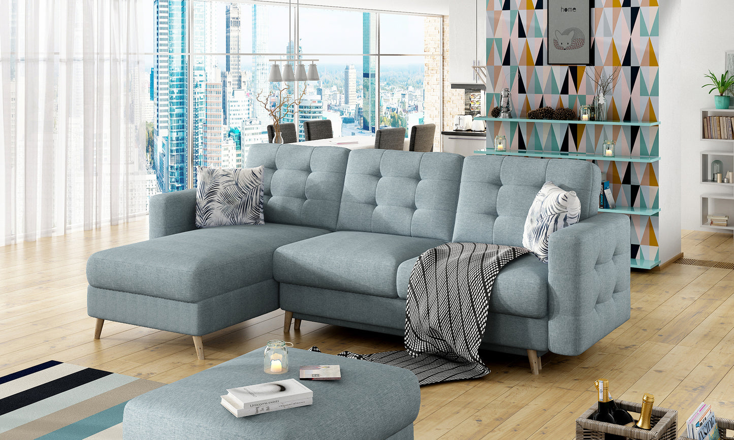 Narożnik Asgard L w tkaninie Cover 70 w kolorze niebieskim, z poduszkami Botanical 80 i czarno-białym pledem, w designerskiej aranżacji z panoramicznymi oknami.