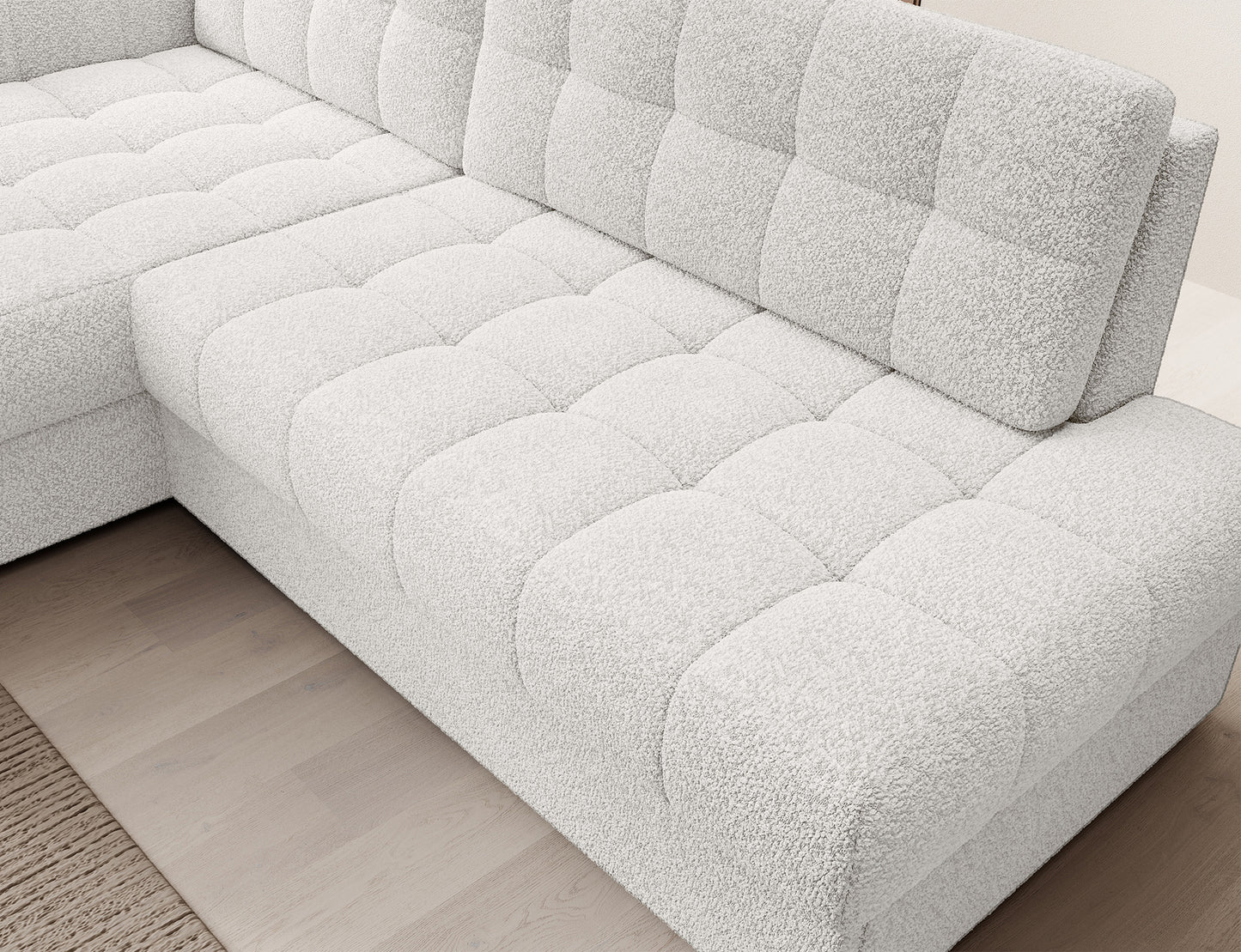 Widok z góry na moduł siedziska narożnika Blezalt lewego Royal 01 w białej tkaninie bouclé, z wyraźnym pikowaniem i podłogą z paneli.