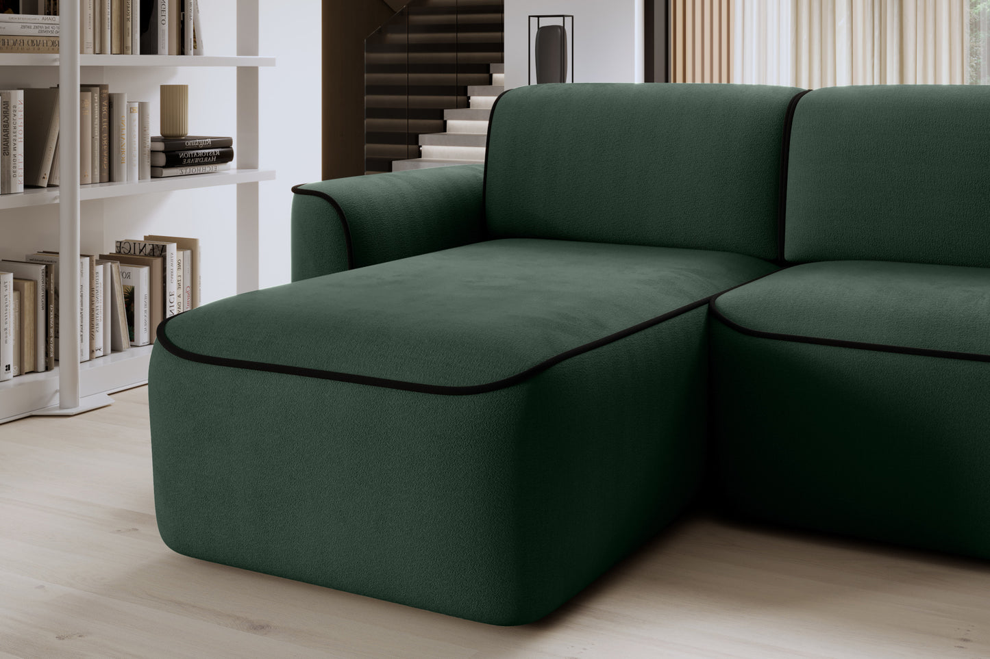 Zbliżenie na siedzisko szezlongu narożnika Ume w Amore 35 ciemnozielonym z lamówką Velvetmat 10 czarną, w tle regał z książkami.