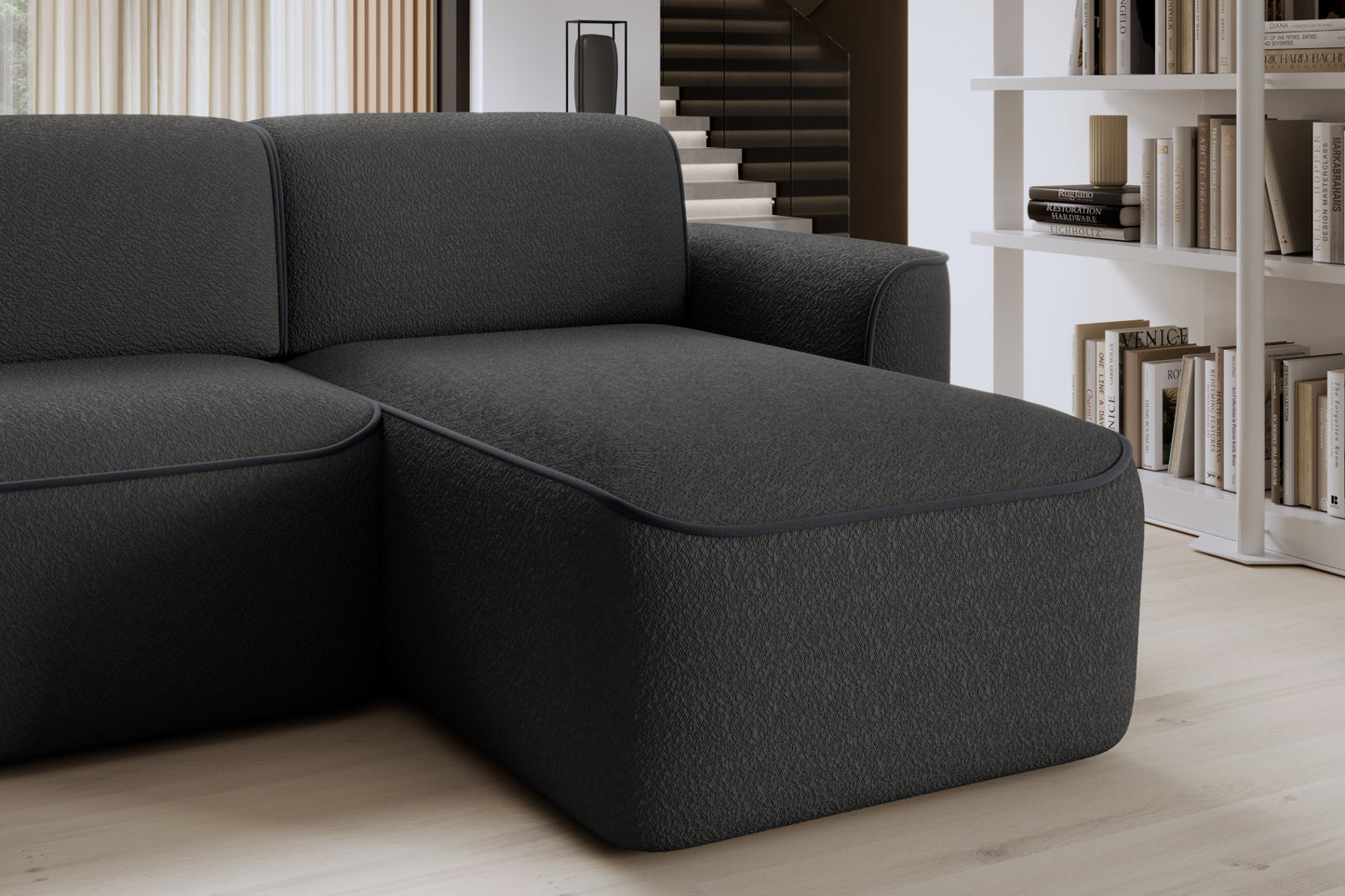 Zbliżenie przedniej krawędzi szezlongu prawej strony narożnika Ume, tapicerka Royal 05 czarny z obwódką Velvetmat 06 ciemnoszary.