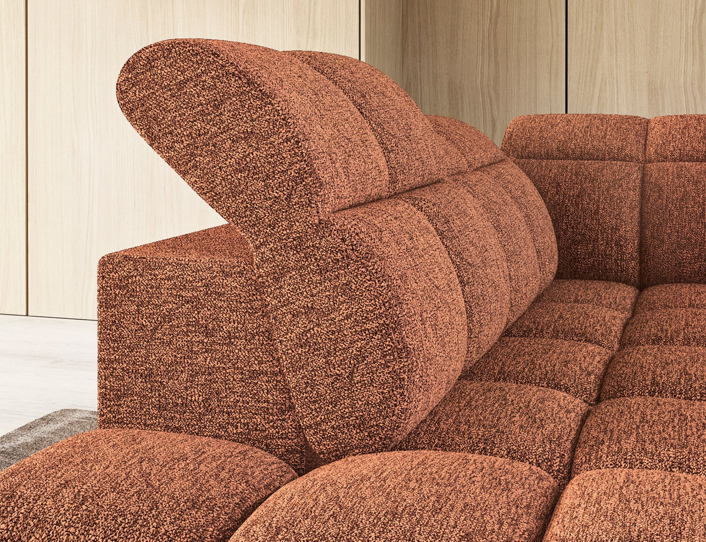 Zbliżenie na narożnik Falconn Coralline 30 w kolorze ceglastym z podniesionym zagłówkiem i tapicerką o wyrazistej fakturze.