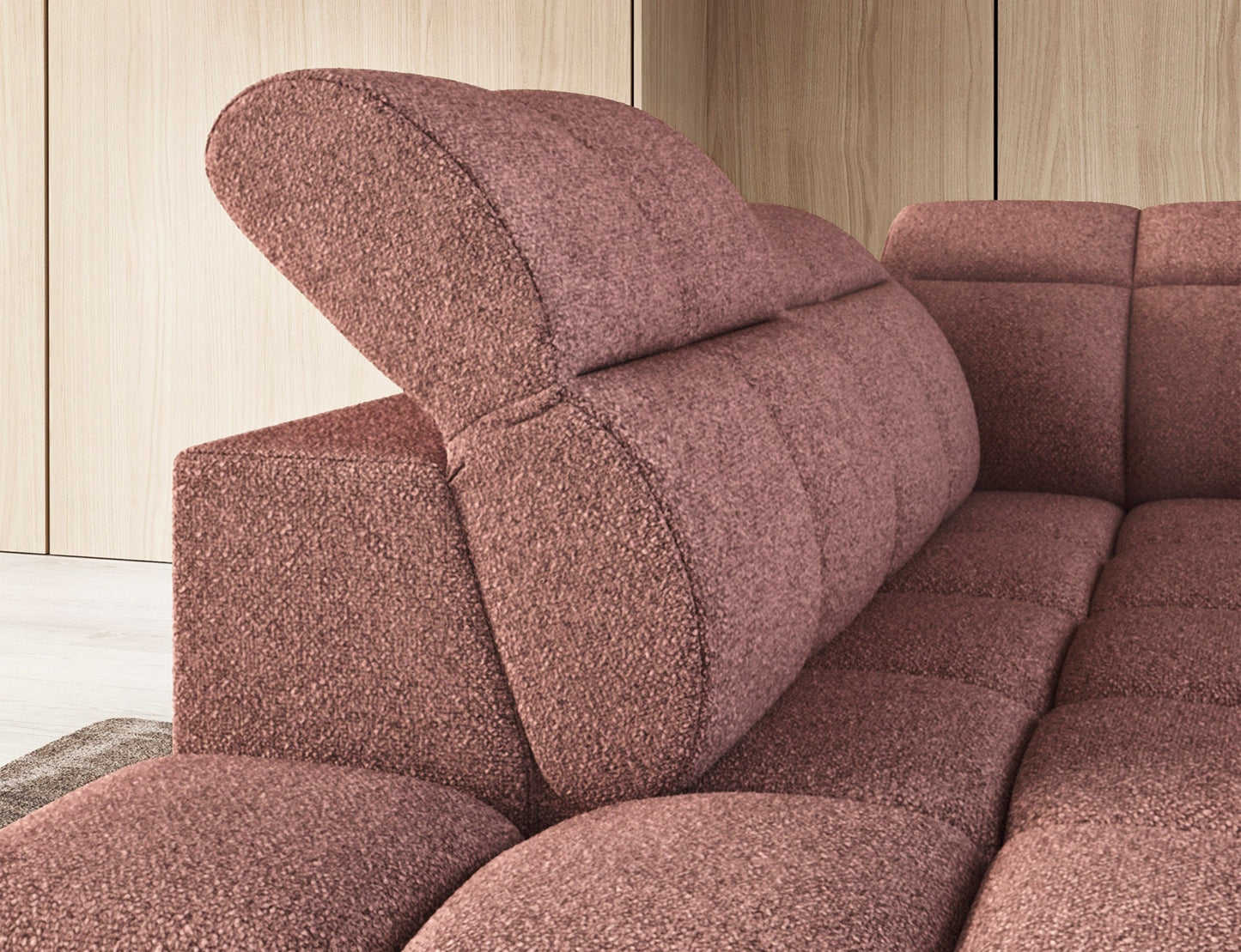 Różowy narożnik Falconn Paolli 24 z podniesionym zagłówkiem, widok z boku na modułowe, pikowane oparcie na tle drewnianej ściany.