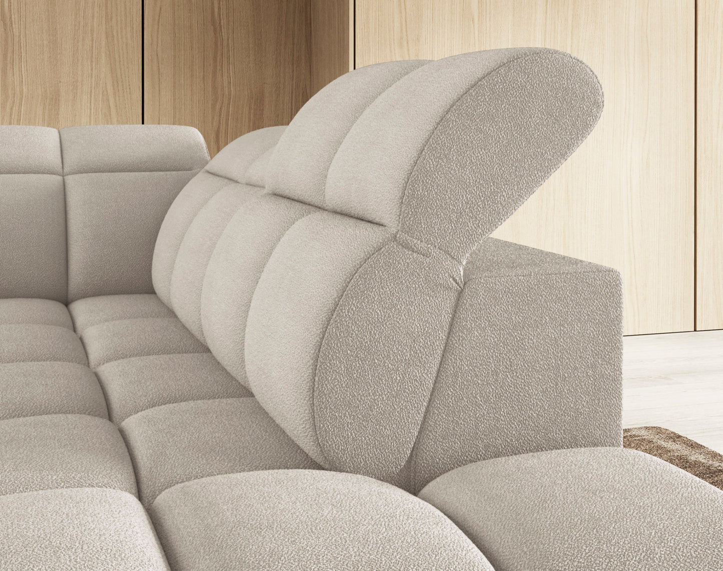 Zbliżenie na regulowane zagłówki narożnika Falconn Royal-18 w jasnej tkaninie bouclé, zapewniające dodatkowy komfort wypoczynku.