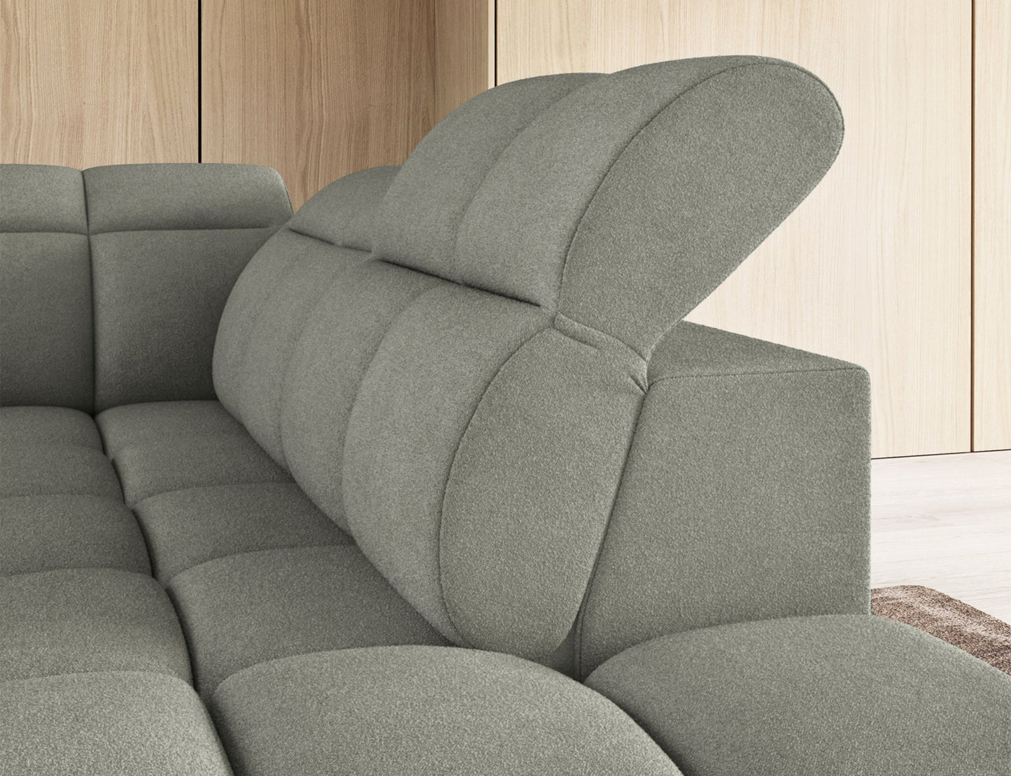 Zbliżenie na regulowany zagłówek narożnika Xillar 100, wykończonego w jasnozielonej tkaninie o miękkiej, pikowanej strukturze.