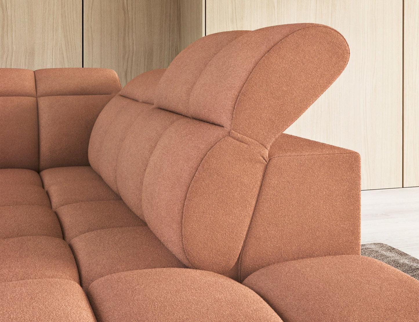 Różowy zagłówek narożnika Xillar 24 z regulacją, ukazany w zbliżeniu na tle pikowanego oparcia i drewnianej ściany.