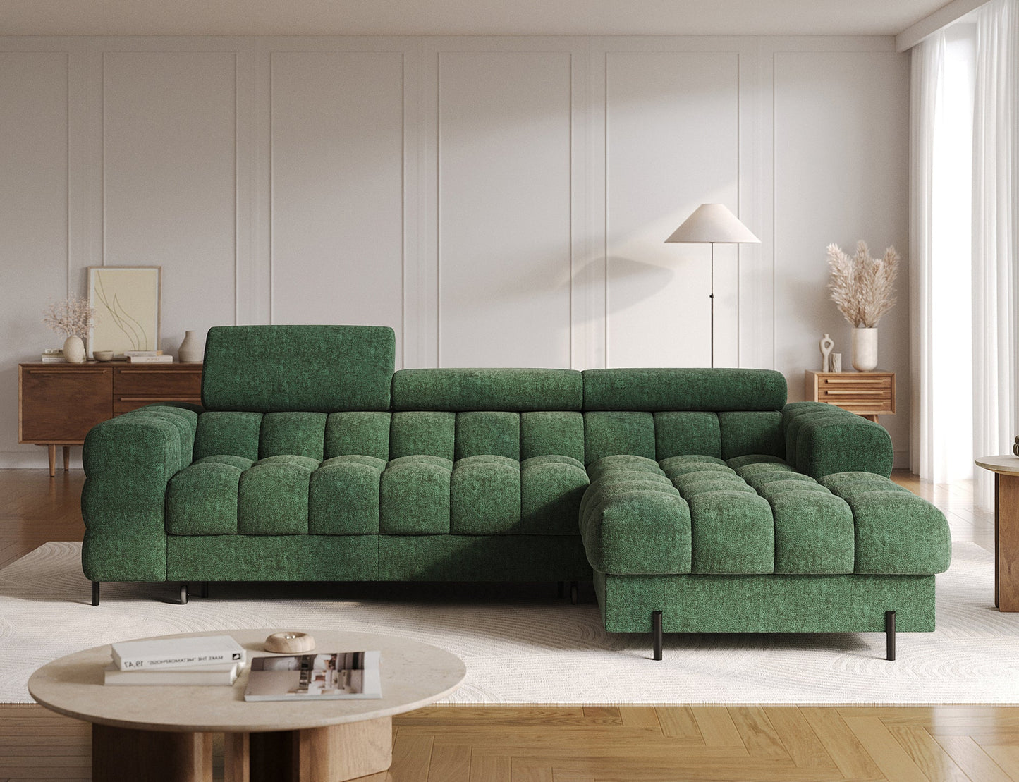 Zielona sofa narożna z pikowanym obiciem w eleganckim wnętrzu, otoczona drewnianymi meblami i jasnymi zasłonami.