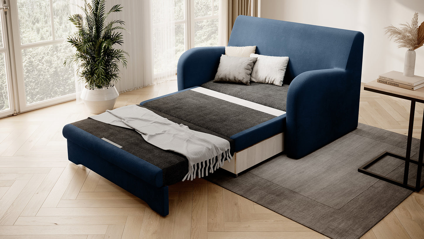 Granatowa sofa Ario w gładkiej tkaninie, rozłożona do spania, ujęcie skośne w salonie na dywanie, obok okna z rośliną i stolika.