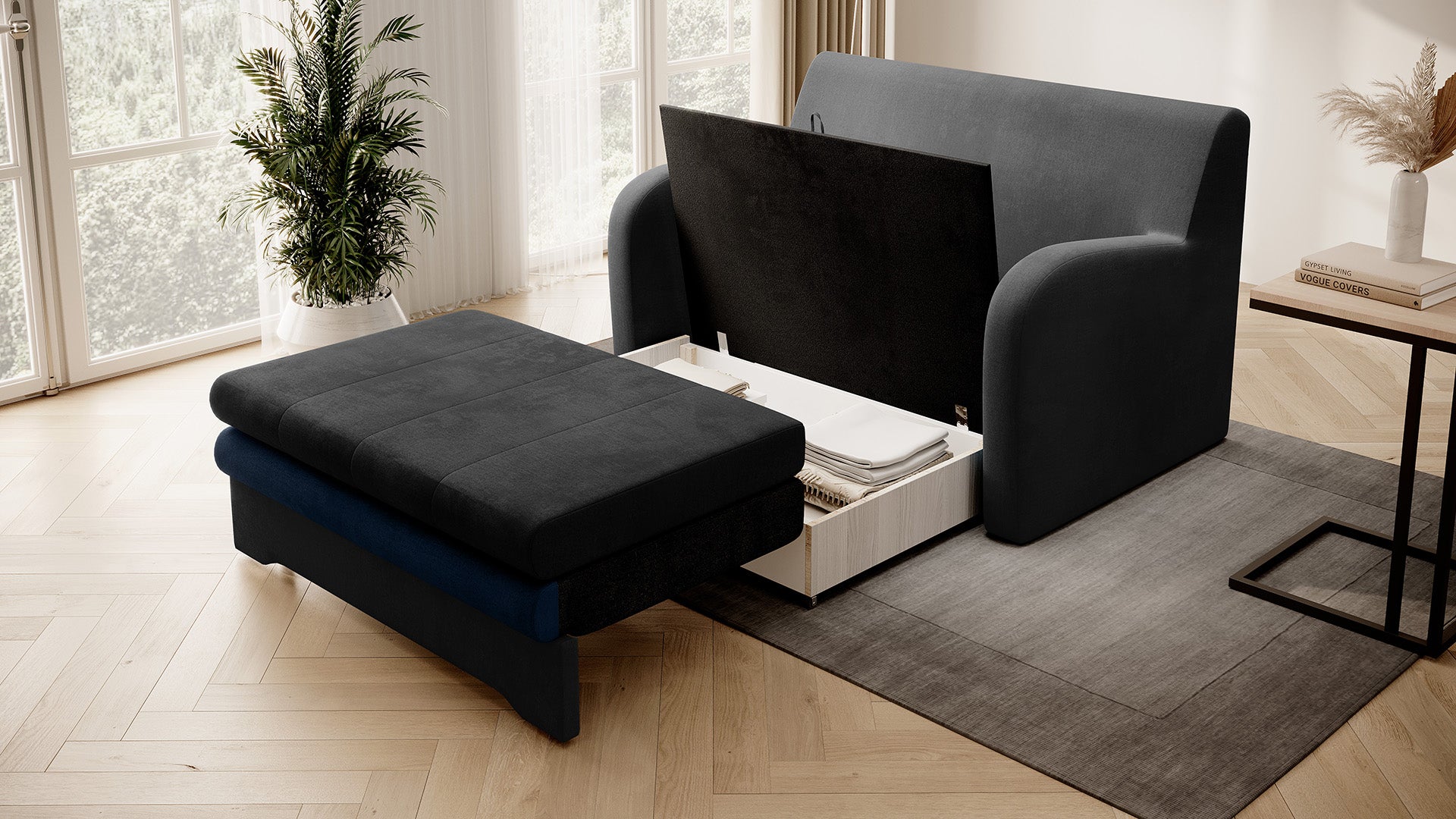 Dwukolorowa sofa Ario (grafit + granat) z otwartym pojemnikiem na pościel; ujęcie skośne.