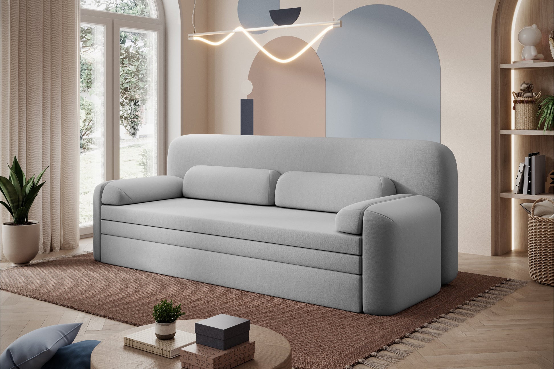 Sofa Elioss Sola 04 jasnoszara – ustawiona w nowoczesnym, kolorowym wnętrzu z dużym oknem i dekoracyjnymi dodatkami