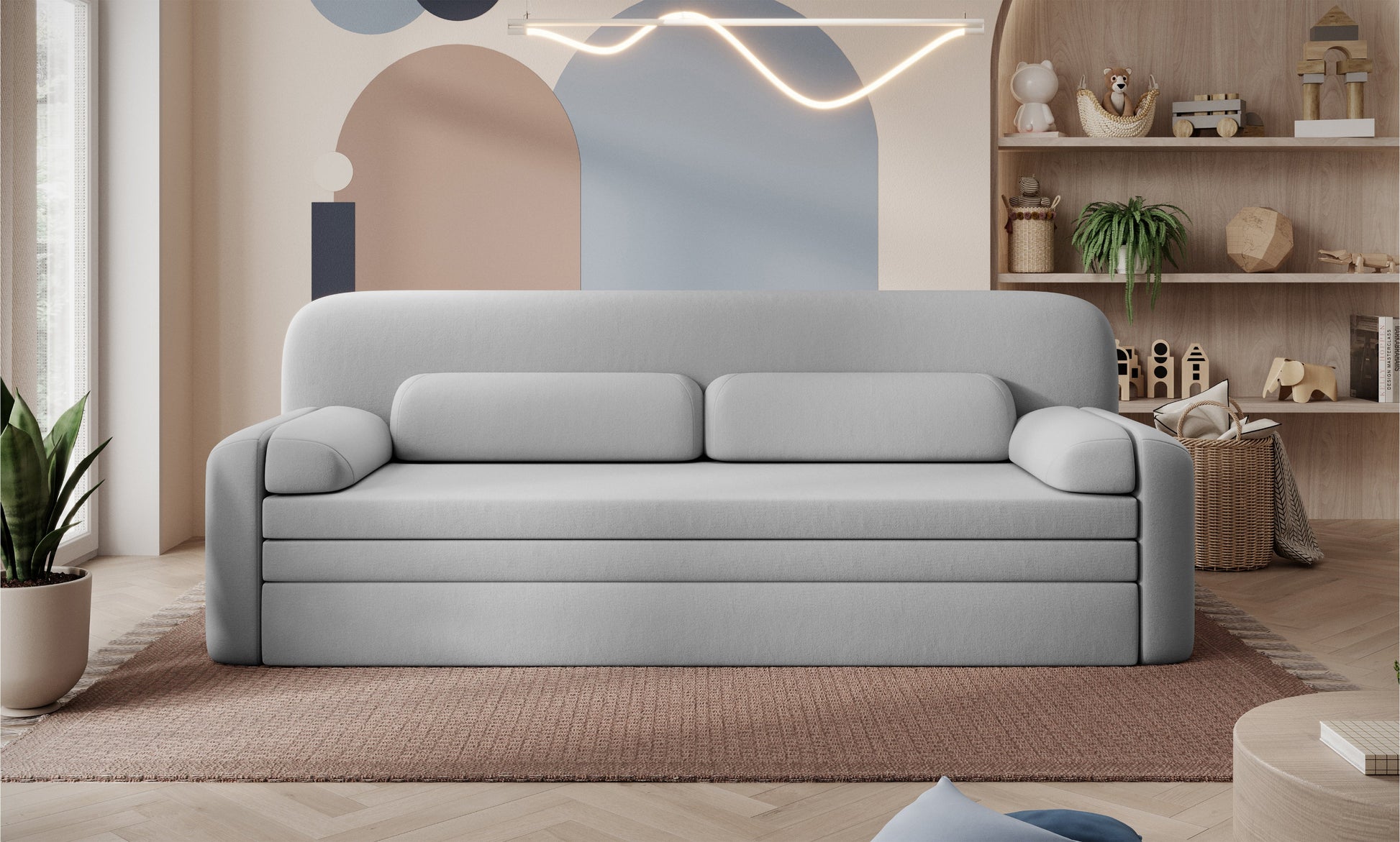 Sofa Elioss Sola 04 w jasnoszarym kolorze na tle kreatywnej aranżacji wnętrza z pastelową ścianą i półkami z zabawkami