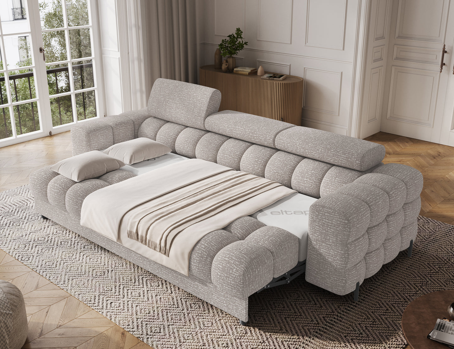 Sofa Festello Baffix 03 jasnoszary z funkcją spania rozłożona w jasnym wnętrzu, komfortowa powierzchnia z pościelą.