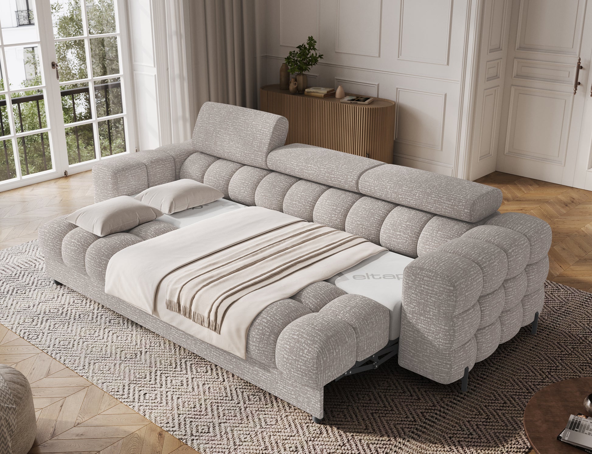 Sofa Festello Baffix 03 jasnoszary z funkcją spania rozłożona w jasnym wnętrzu, komfortowa powierzchnia z pościelą.
