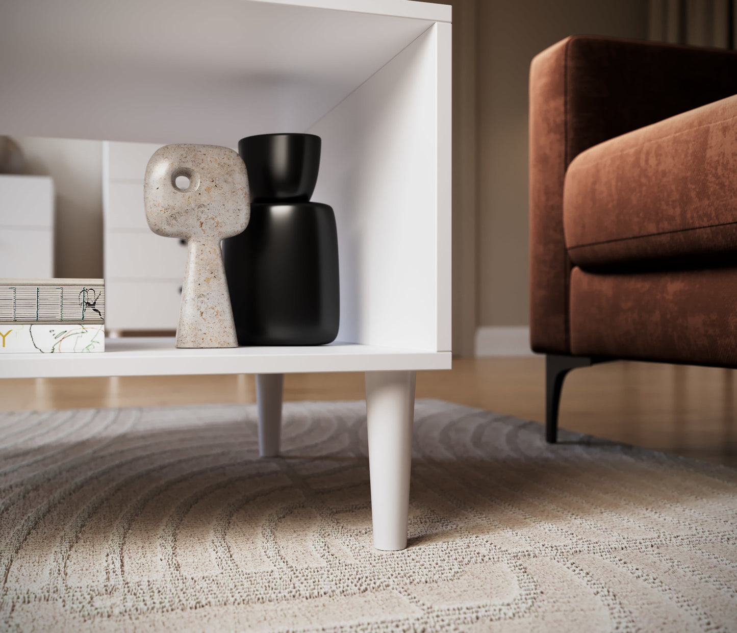 Zbliżenie na dolną półkę białego stolika kawowego Dullum – eleganckie dekoracje i detale nóg stożkowych na tle dywanu w jasnych tonacjach.