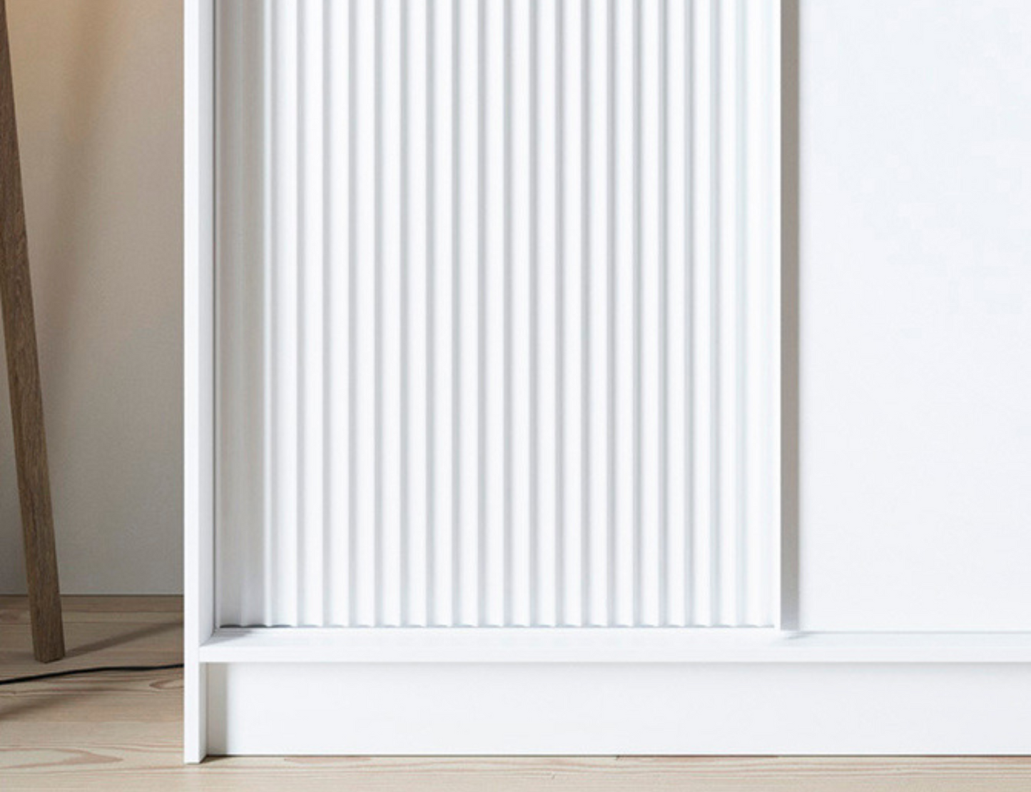 Zbliżenie na ryflowane drzwi szafy Biancco III w białym kolorze, łączące minimalistyczny styl z eleganckim wykończeniem frontów.