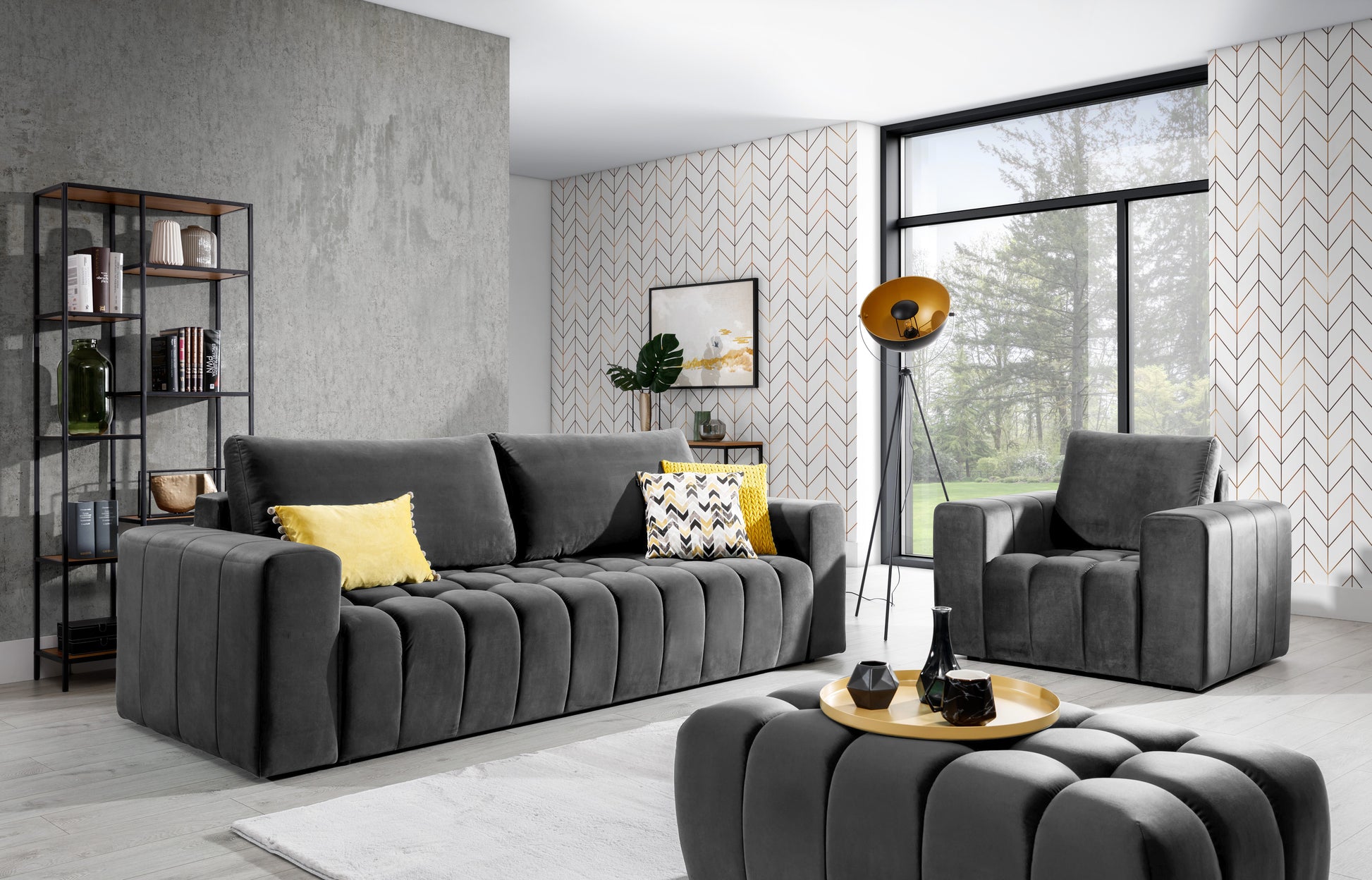 Zestaw wypoczynkowy Lazaro w kolorze Nube 05 ciemnoszary ustawiony w nowoczesnym salonie z dużym oknem, fotel i sofa ozdobione poduszkami dekoracyjnymi, pufa pełniąca funkcję stolika.