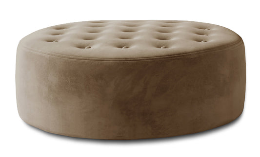 Jasnobrązowa pufa Monty w tkaninie Monolith 09 pokazana jako okrągły mebel tapicerowany z miękkim siedziskiem, dekoracyjnym pikowaniem i przytulną strukturą materiału.