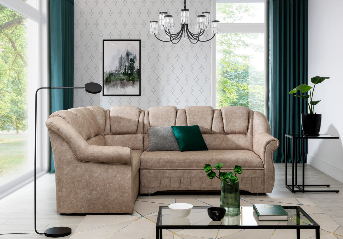 Beżowy narożnik Lord II lewy w tkaninie Dora 21 ustawiony w eleganckim salonie z dużymi oknami i nowoczesnymi dodatkami. Stylowy narożnik do wnętrz modern classic, glamour oraz przytulnych aranżacji rodzinnych.
