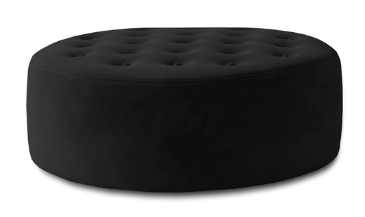 Czarna pufa Monty w tkaninie Matt Velvet 99 pokazana na jasnym tle jako okrągły mebel tapicerowany z miękkim siedziskiem i dekoracyjnym pikowaniem.