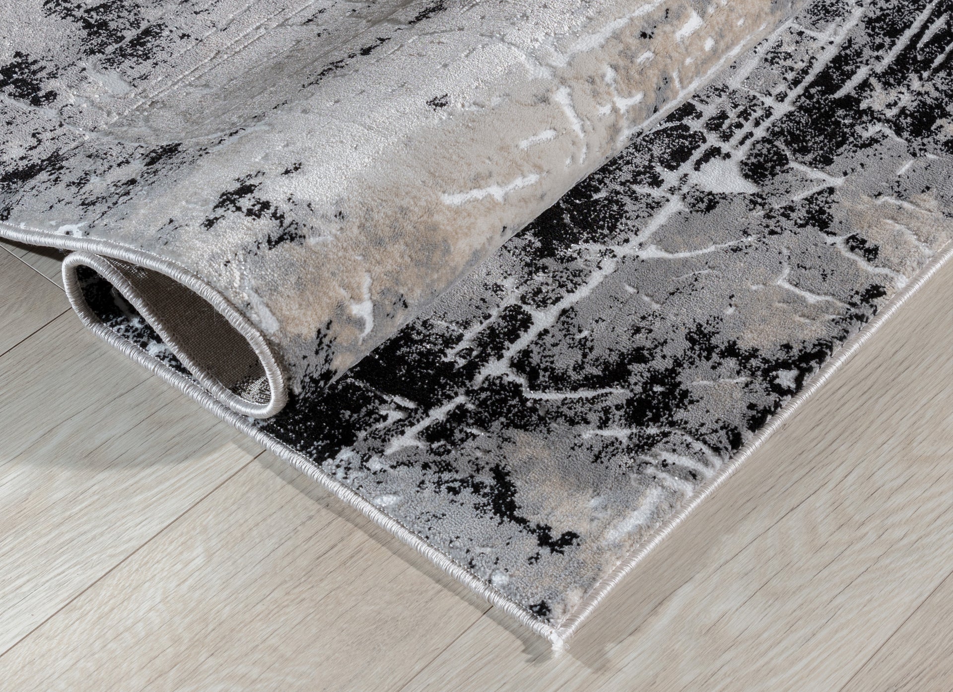 Dywan Bardot Grey 80x150 cm w nowoczesnym salonie z szarą sofą i granatowymi poduszkami.