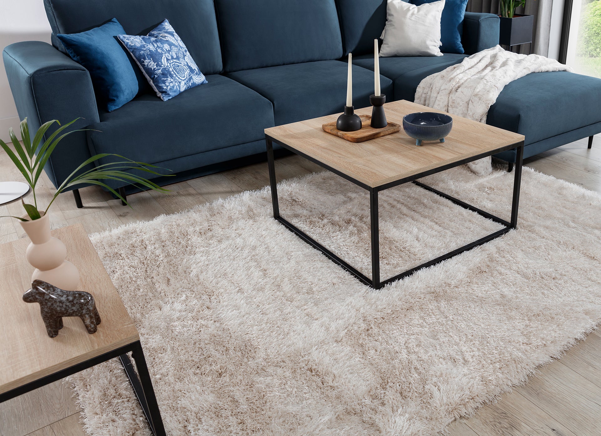 Zbliżenie na krawędź dywanu Blodwen Beige, ukazujące miękkie, połyskujące włókna i puszystą fakturę.