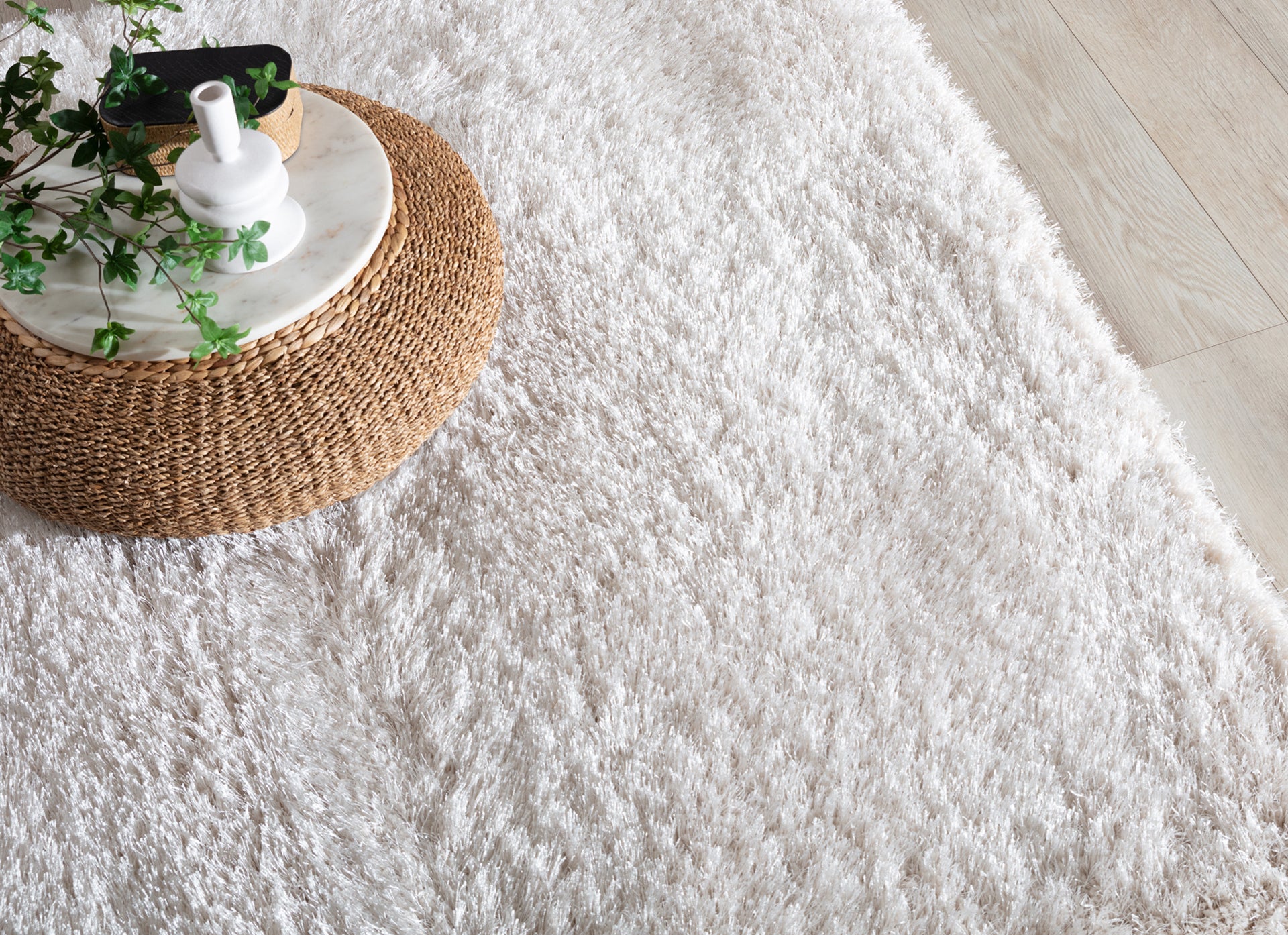 Dywan Blodwen Beige 80x150 cm w aranżacji z plecionym stolikiem i dekoracjami w naturalnym stylu.