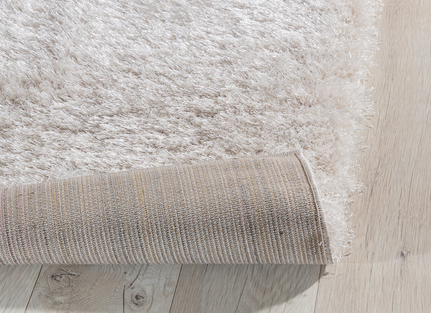 Zagięty róg dywanu Blodwen Beige 80x150 cm, prezentujący elastyczność i solidne podszycie.