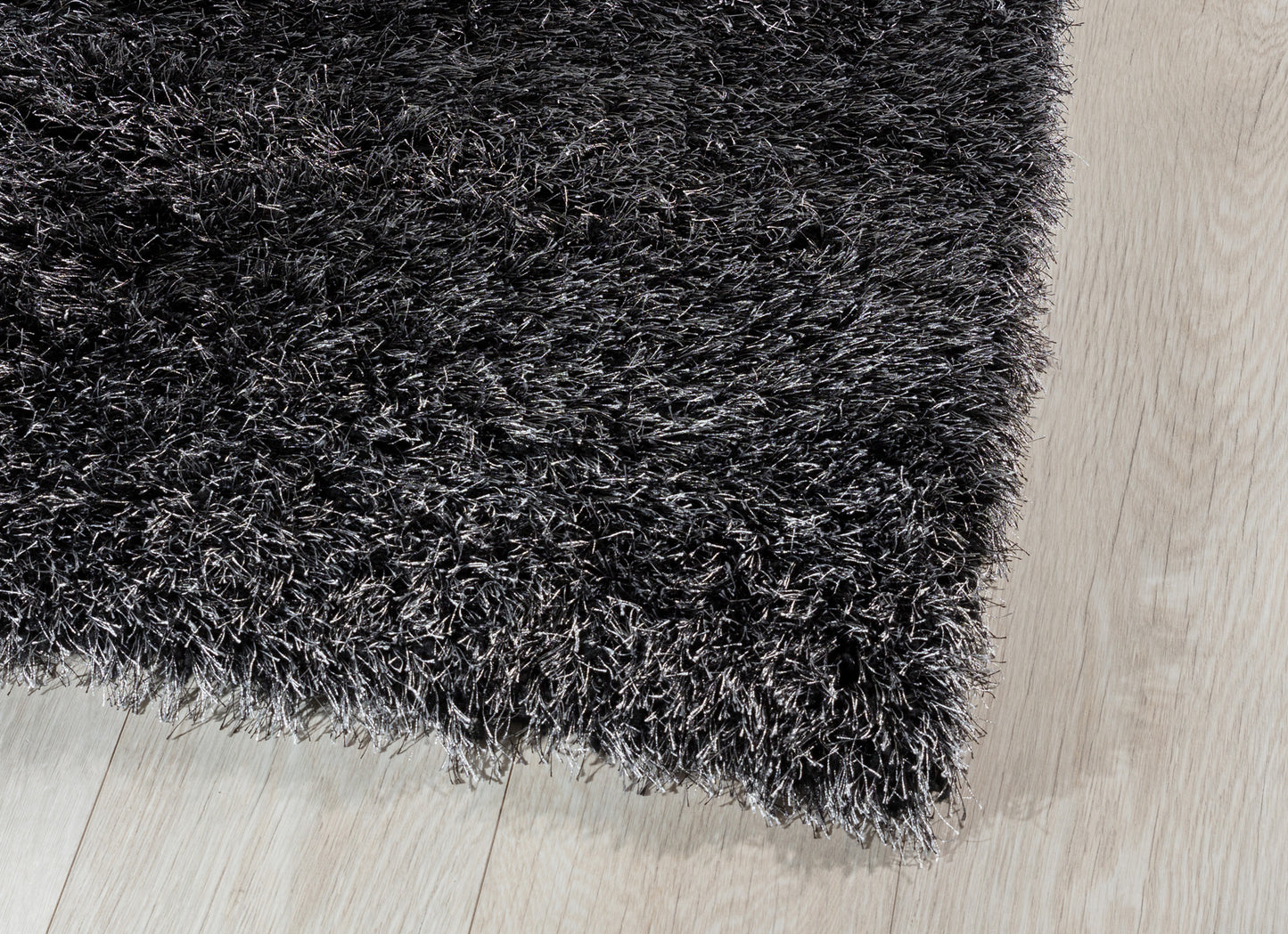 Zbliżenie na krawędź dywanu Blodwen Black, ukazujące wysokie włosie i połyskującą fakturę.