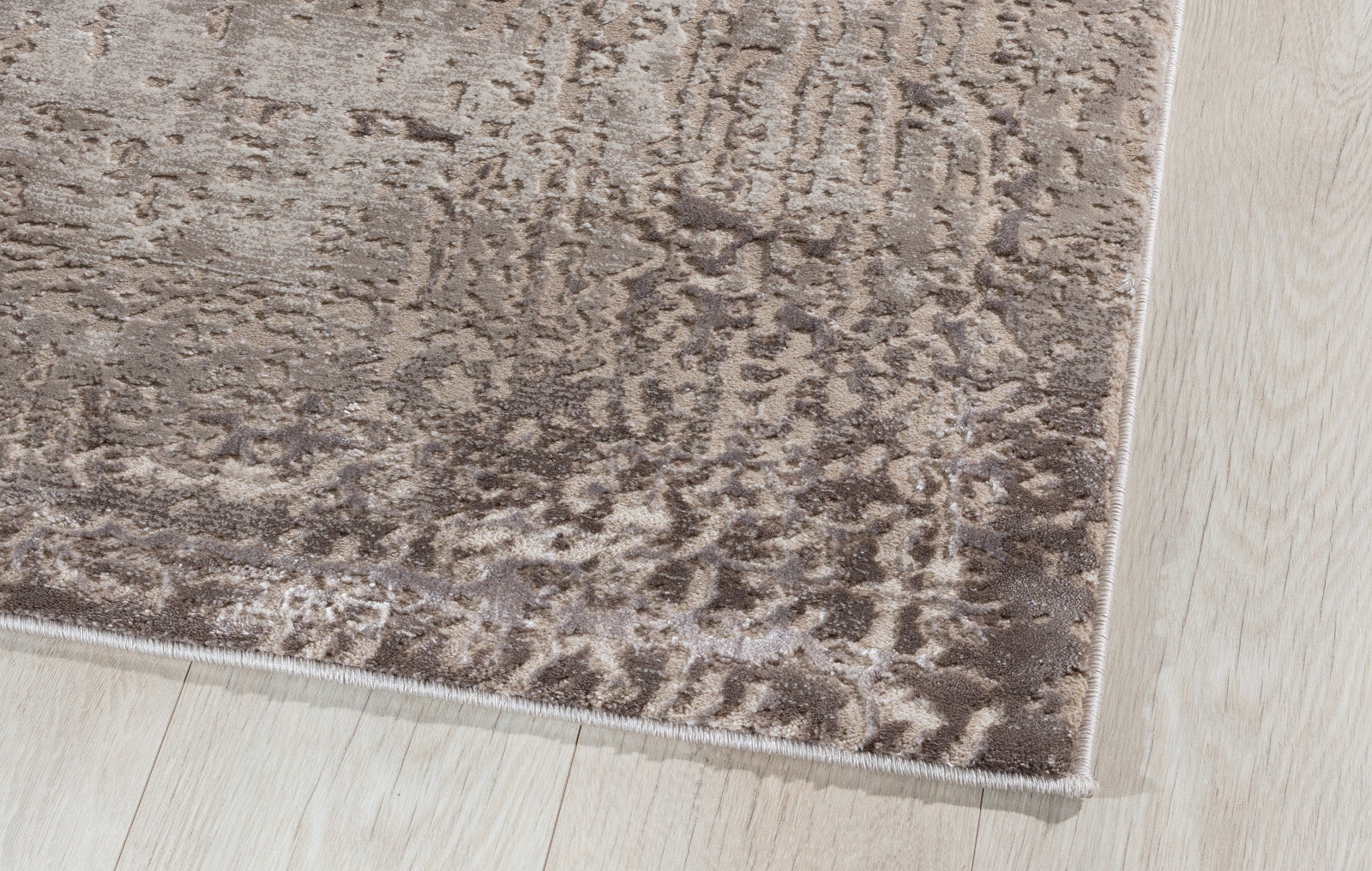 Zbliżenie na krawędź dywanu Codrila Beige, ukazujące gęsty splot, miękką powierzchnię i eleganckie wykończenie.