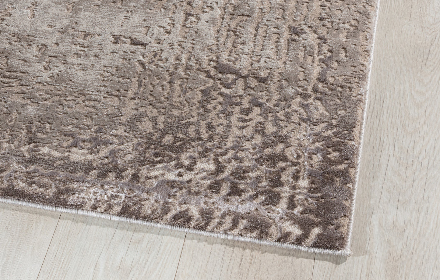 Zbliżenie na krawędź dywanu Codrila Beige, ukazujące gęsty splot, miękką powierzchnię i staranne obszycie.