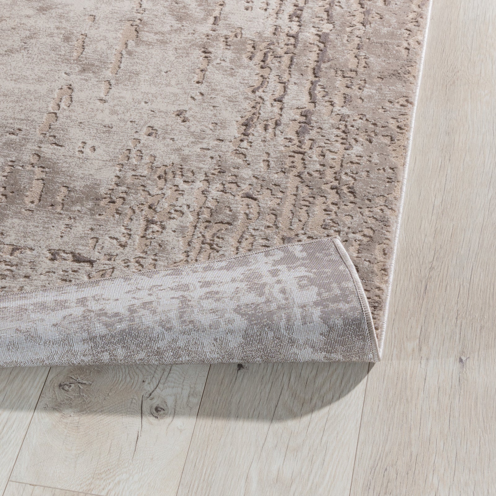 Zagięty róg dywanu Codrila Beige 160x220 cm, pokazujący elastyczność tkaniny i trwałe wykończenie.