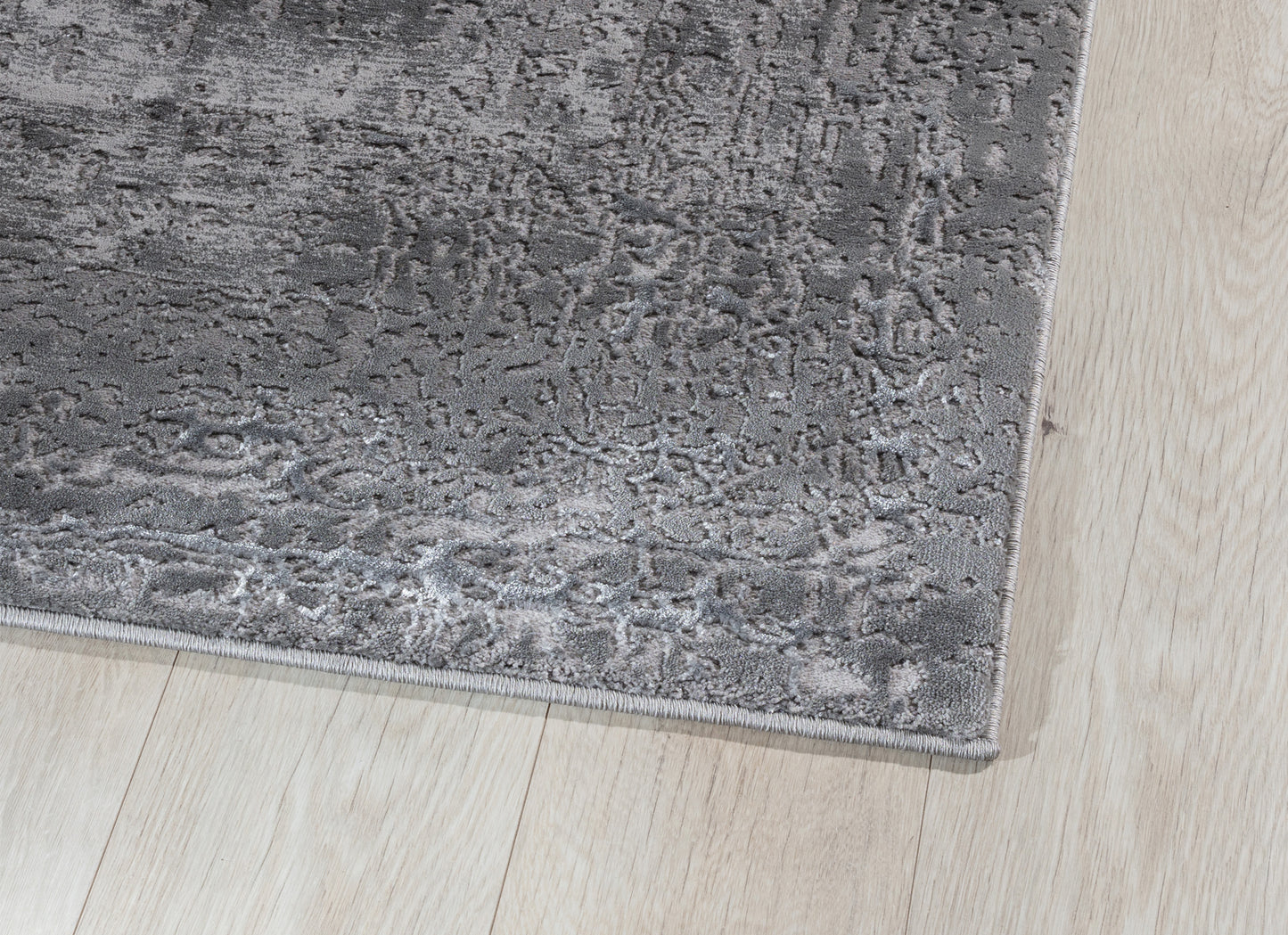 Zbliżenie na krawędź dywanu Codrila Grey, ukazujące gęsty splot, miękką powierzchnię i staranne obszycie.