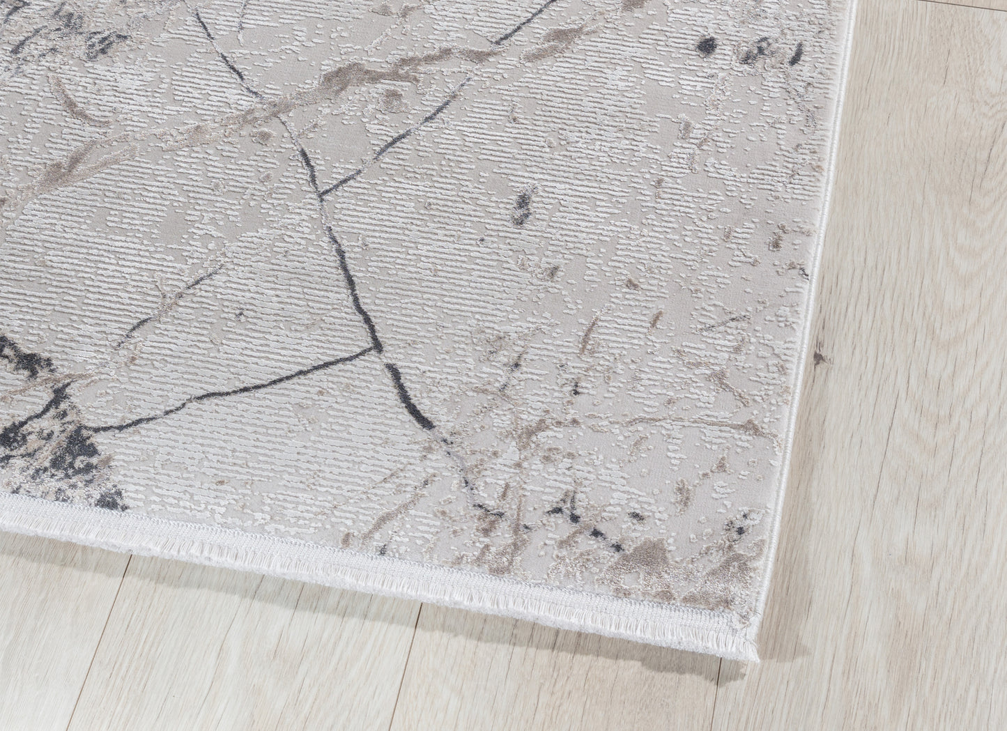 Detal krawędzi dywanu Collymore Beige 160x230 cm – widoczne wykończenie z krótkim obszyciem na tle jasnej podłogi.