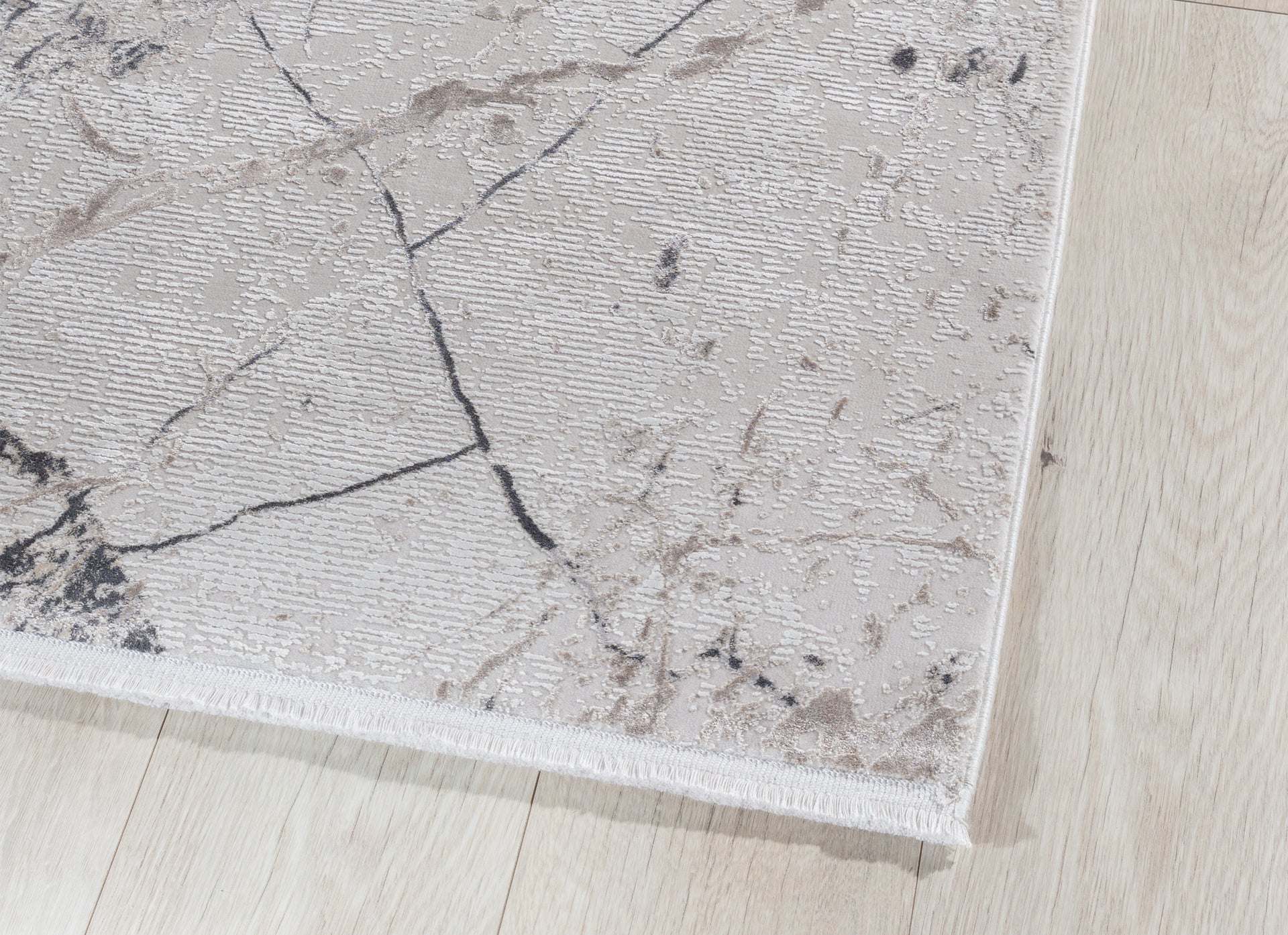 Detal krawędzi dywanu Collymore Beige 160x230 cm – widoczne wykończenie z krótkim obszyciem na tle jasnej podłogi.