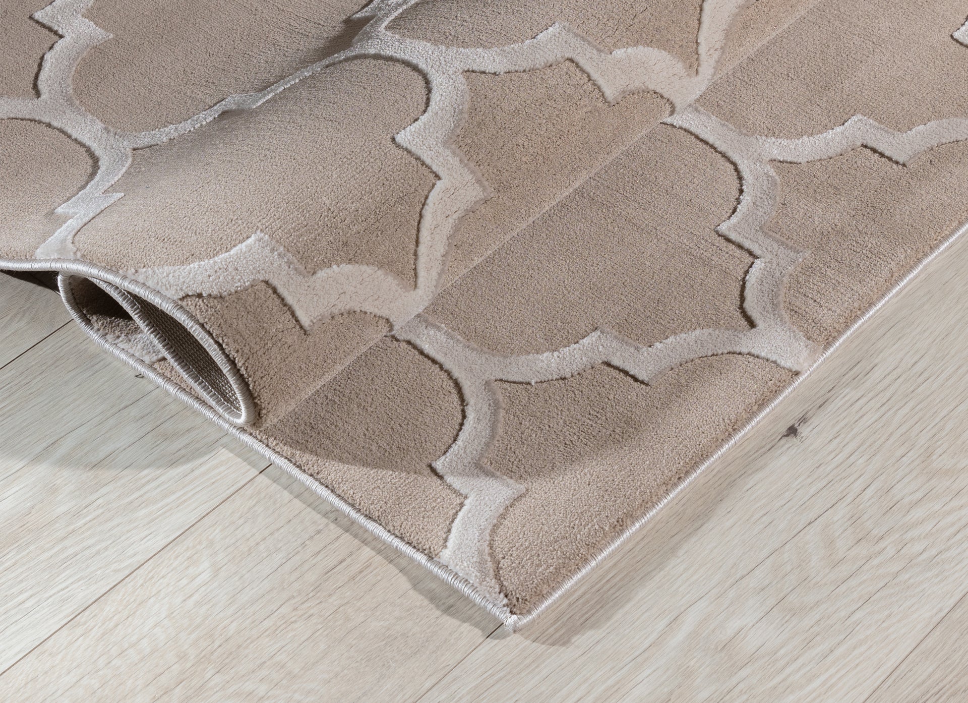 Dywan Elsher Beige 120x180 cm zwinięty w rulon, prezentujący puszystą fakturę i geometryczny wzór w odcieniach beżu.